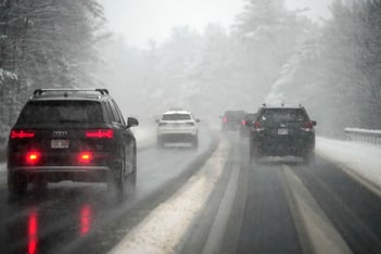 Cars drive through a snowstorm.