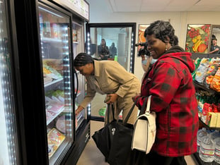 Jasmine Crowe-Houston bends down to pick up an item from a freezer. Leandre Bigby stands next to her.