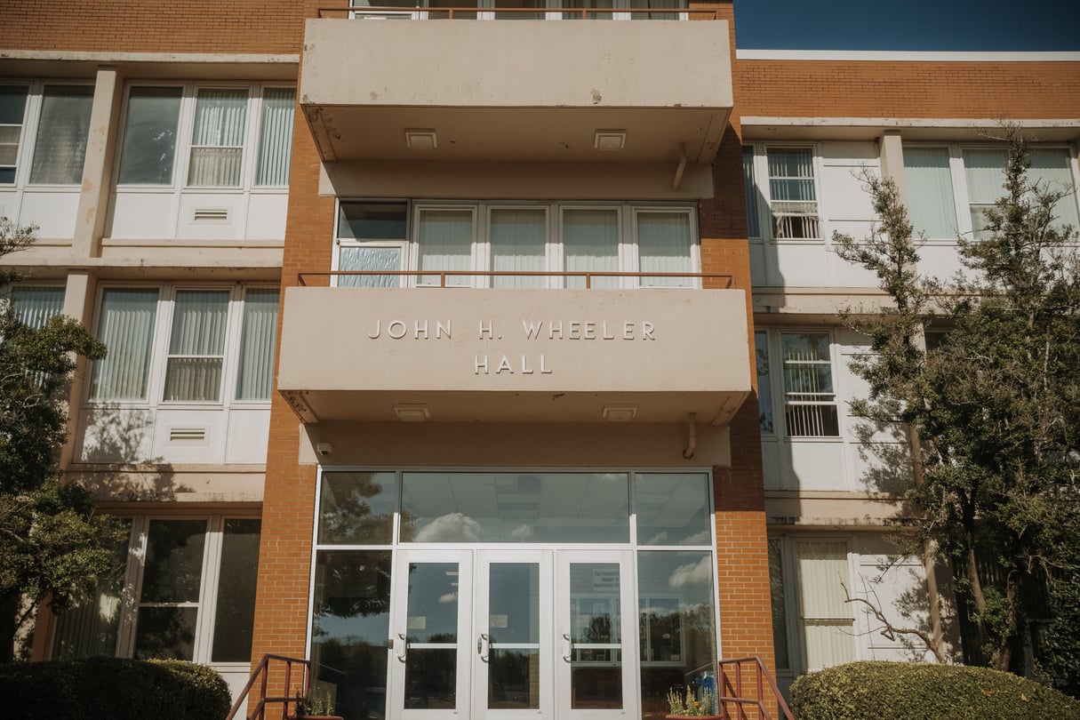 An orange brick building with the words John H. Wheeler on it.