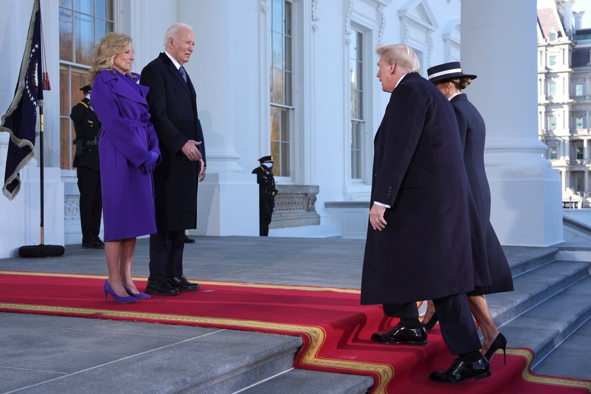 President Joe Biden and First Lady Jill Biden stand on the steps of the White House, facing Donald Trump and Melania Trump as they make their way up the steps.
