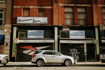 A brick storefront with a white car in front of it