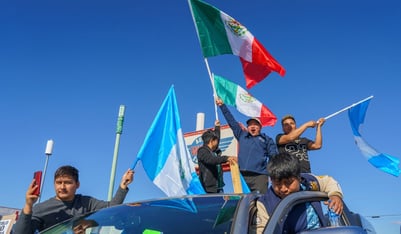 Protesters waving flags stand on top of a car at a rally in Buford Highway on Saturday, Feb, 1, 2025, against recent Immigration and Customs Enforcements arrests.