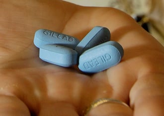 Four blue pills in the palm of a person's hand.