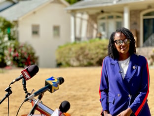 Mayor Donya Sartor standing in front of a microphone stand for a press conference.