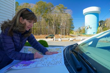 A woman looks at a map on the hood of a car