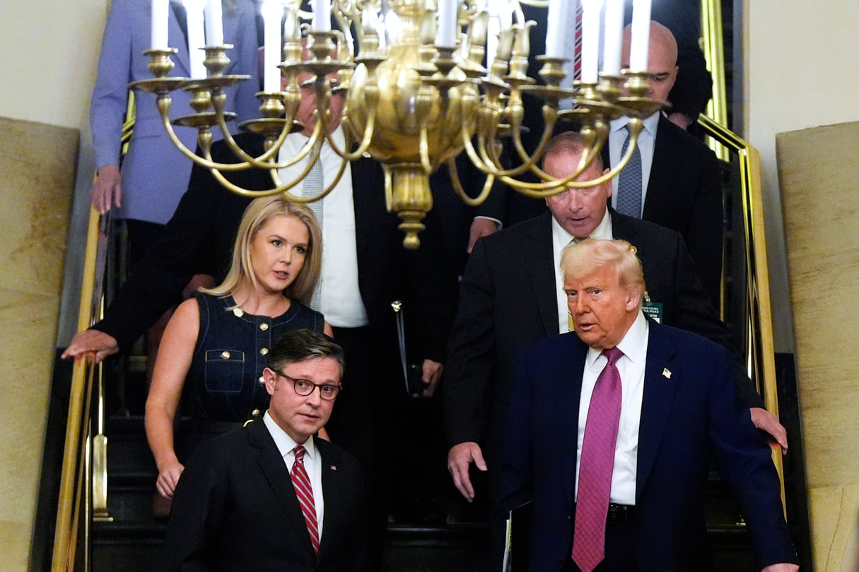 Several people walk down a stairwell, including House Speaker Mike Johnson and President Donald Trump, who are talking to each other.