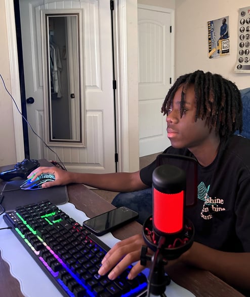 A young man sitting in front of his desk with a LED keyboard.