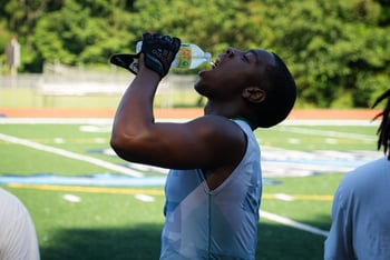 Cedar Grove football player drinks water on a hot day at practice.