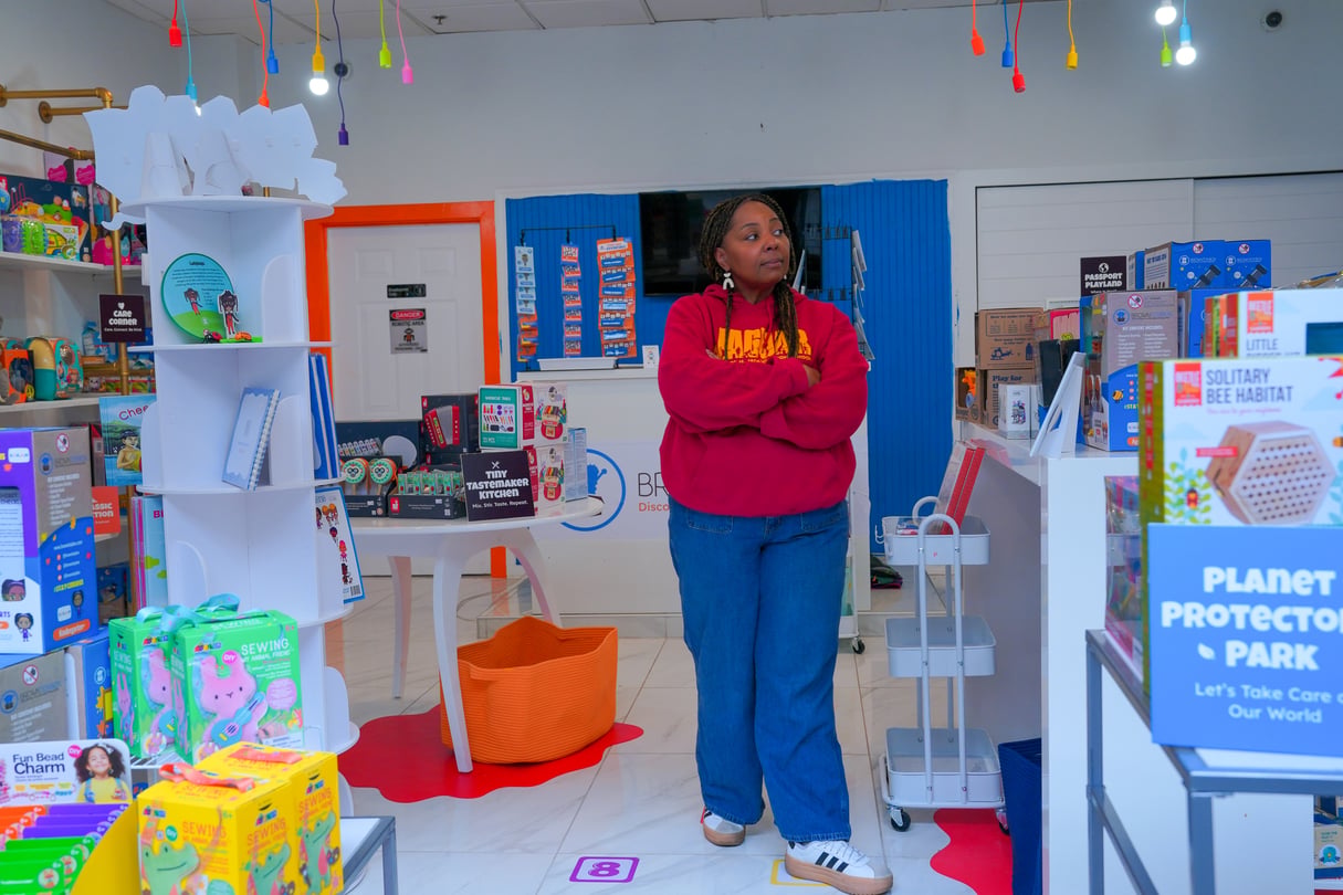 A woman standing alone in her toy store.
