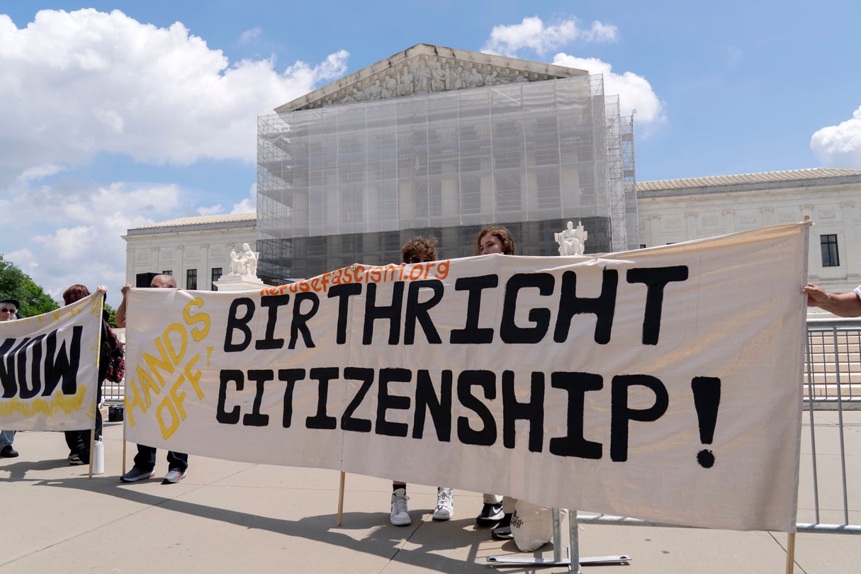 Demonstrators outside of the Supreme Court rally in support for birthright citizenship, holding a large white banner.