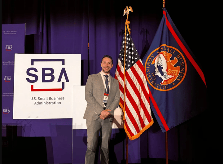 A man poses in front of an SBA sign.