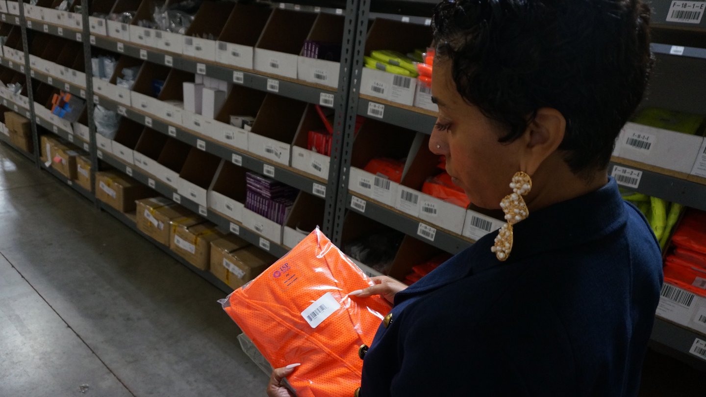 A woman holding a bright orange vest.