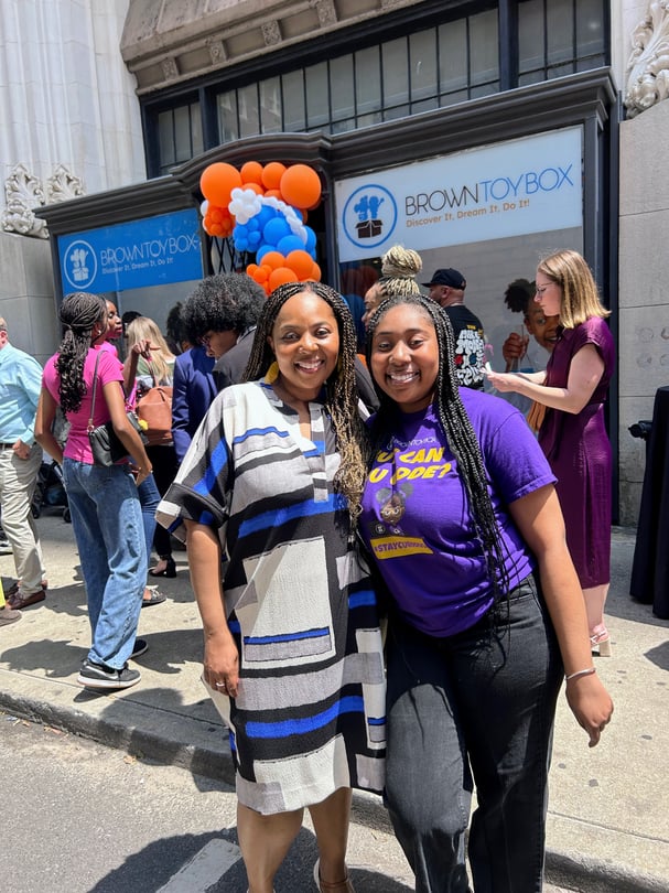 A woman and her daughter standing in front of their newly opened store.