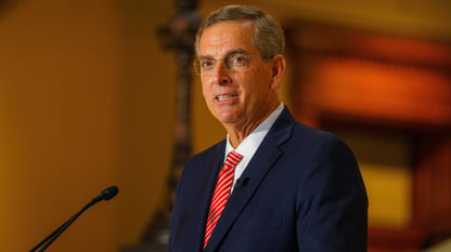 Brad Raffensperger speaking into a microphone at a podium