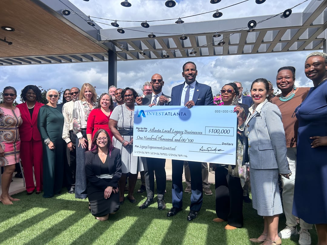 A group of people holding a large check standing on a rooftop.