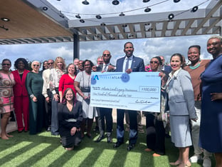 A group of people holding a large check standing on a rooftop.
