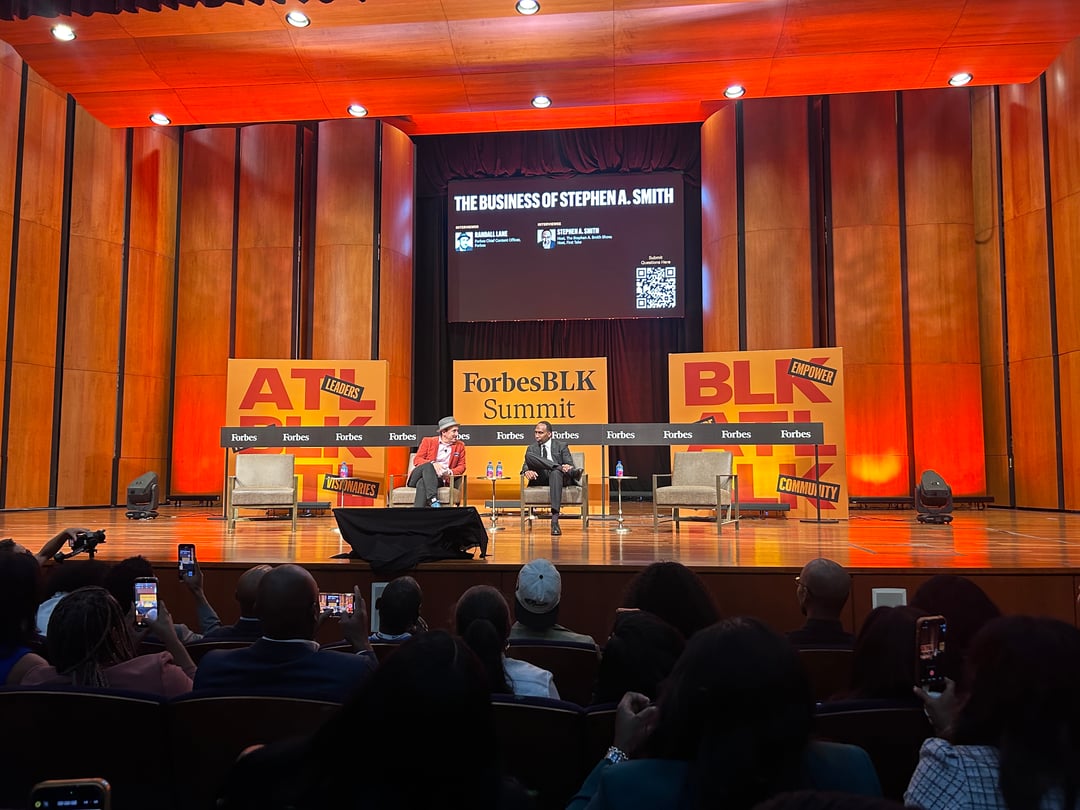 Two people sitting on stage having a chat in front of an audience.