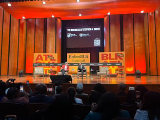 Two people sitting on stage having a chat in front of an audience.