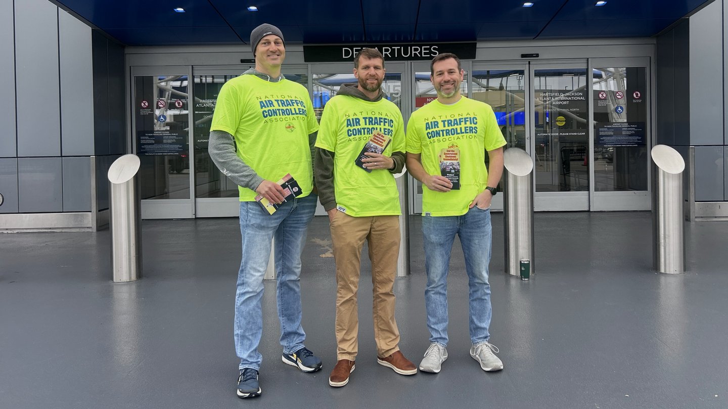 Three guys posing and taking a photo with pamphlets in their hand.