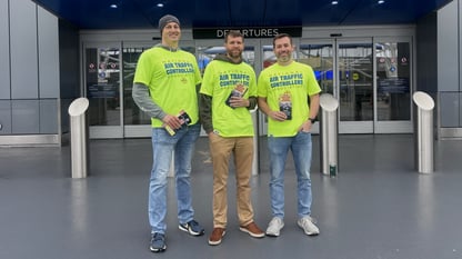Three guys posing and taking a photo with pamphlets in their hand.