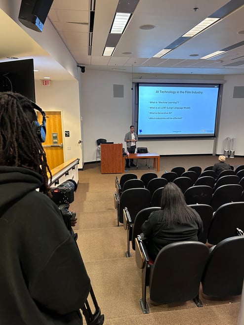 A man records his class in the back of a lecture hall.