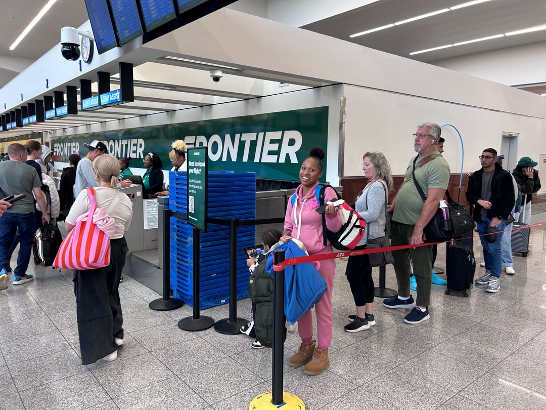 A woman smiles as she waits in line at an airport.