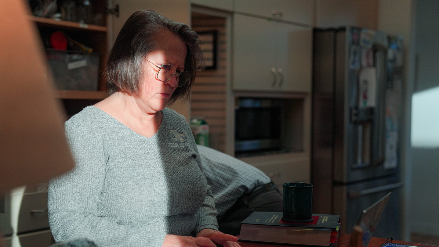 A woman looks at a computer on a kitchen counter