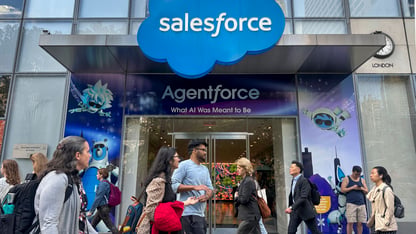 People walk outside a Salesforce office with a blue logo