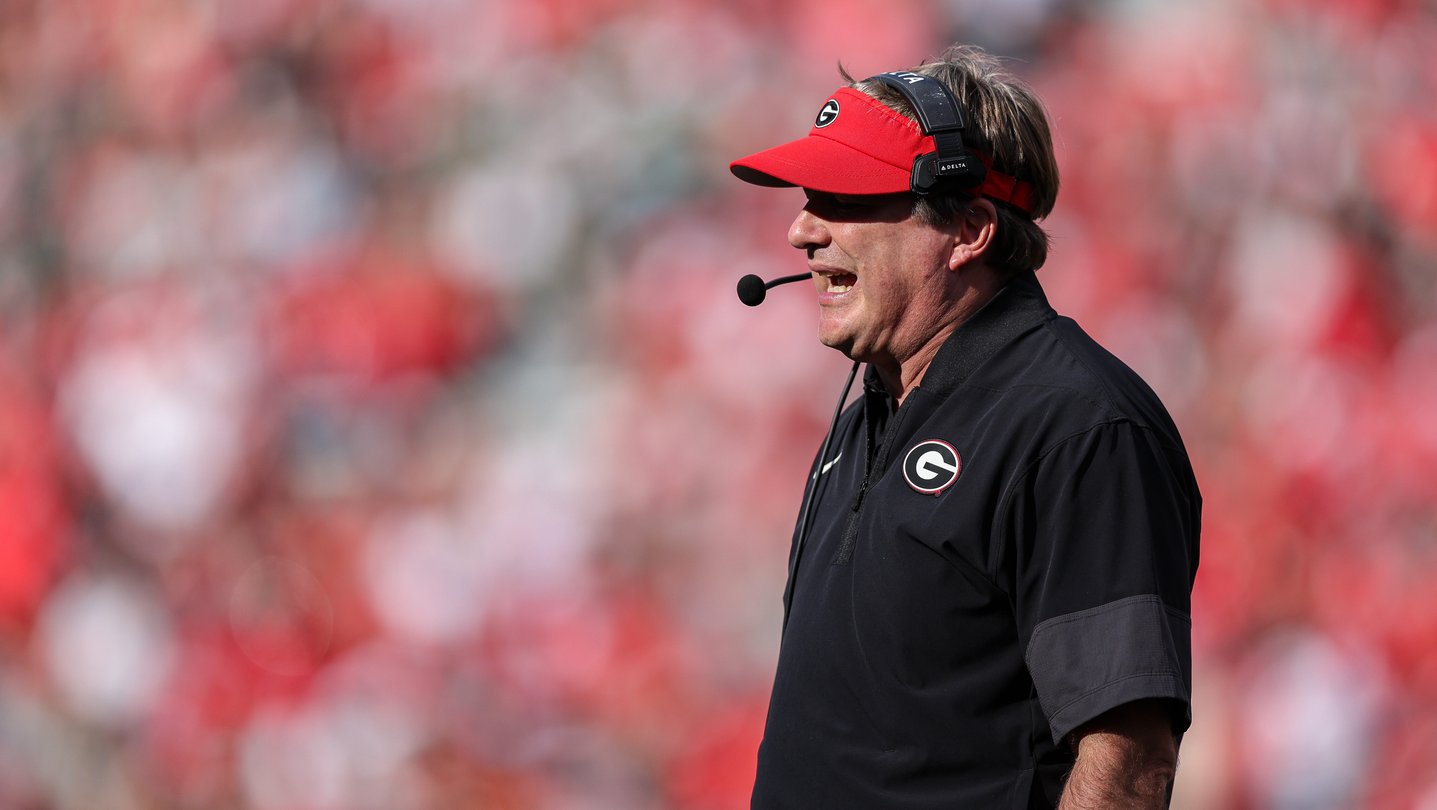 Georgia head coach Kirby Smart wears a red visor and speaks into a headset during a football game