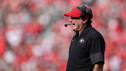 Georgia head coach Kirby Smart wears a red visor and speaks into a headset during a football game