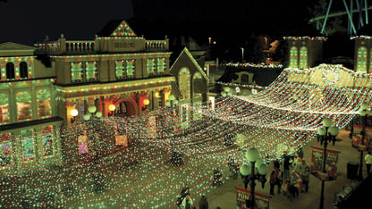 A green tinted amusement park street with glittering string lights