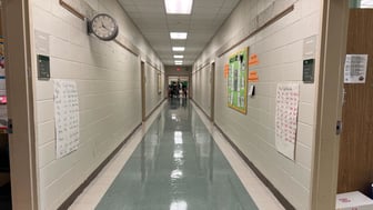 A hallway with white walls and blue floors located at Cleveland Avenue Elementary School.