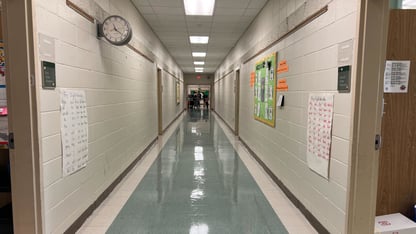 A hallway with white walls and blue floors located at Cleveland Avenue Elementary School.