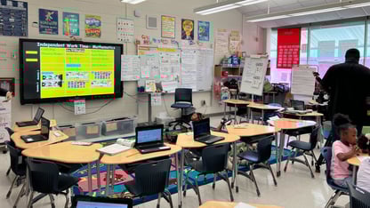 A classroom setting with a Smartboard and several desks around it.