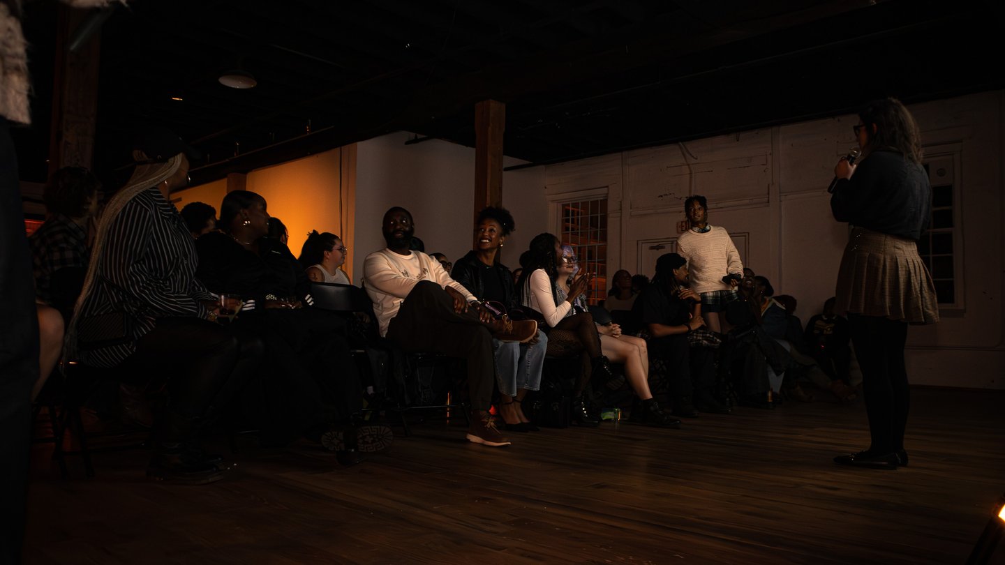 A woman speaks to an audience before playing movies for them.
