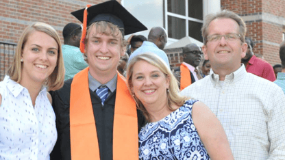 A family with a college graduate wearing graduation robes.
