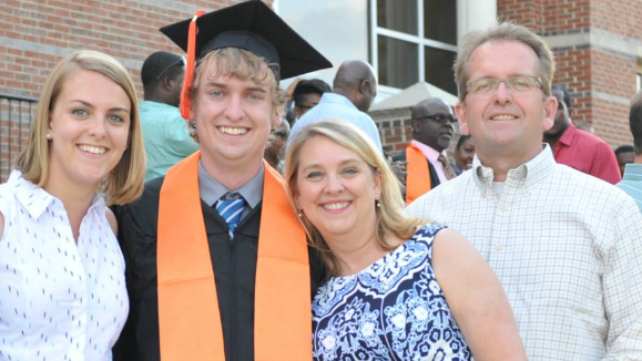 A family with a college graduate wearing graduation robes.