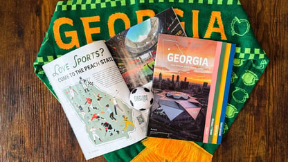The 2026 Georgia Travel Guide on top of a Georgia scarf