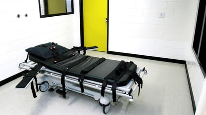 A gurney with arm and body restraints in a white room