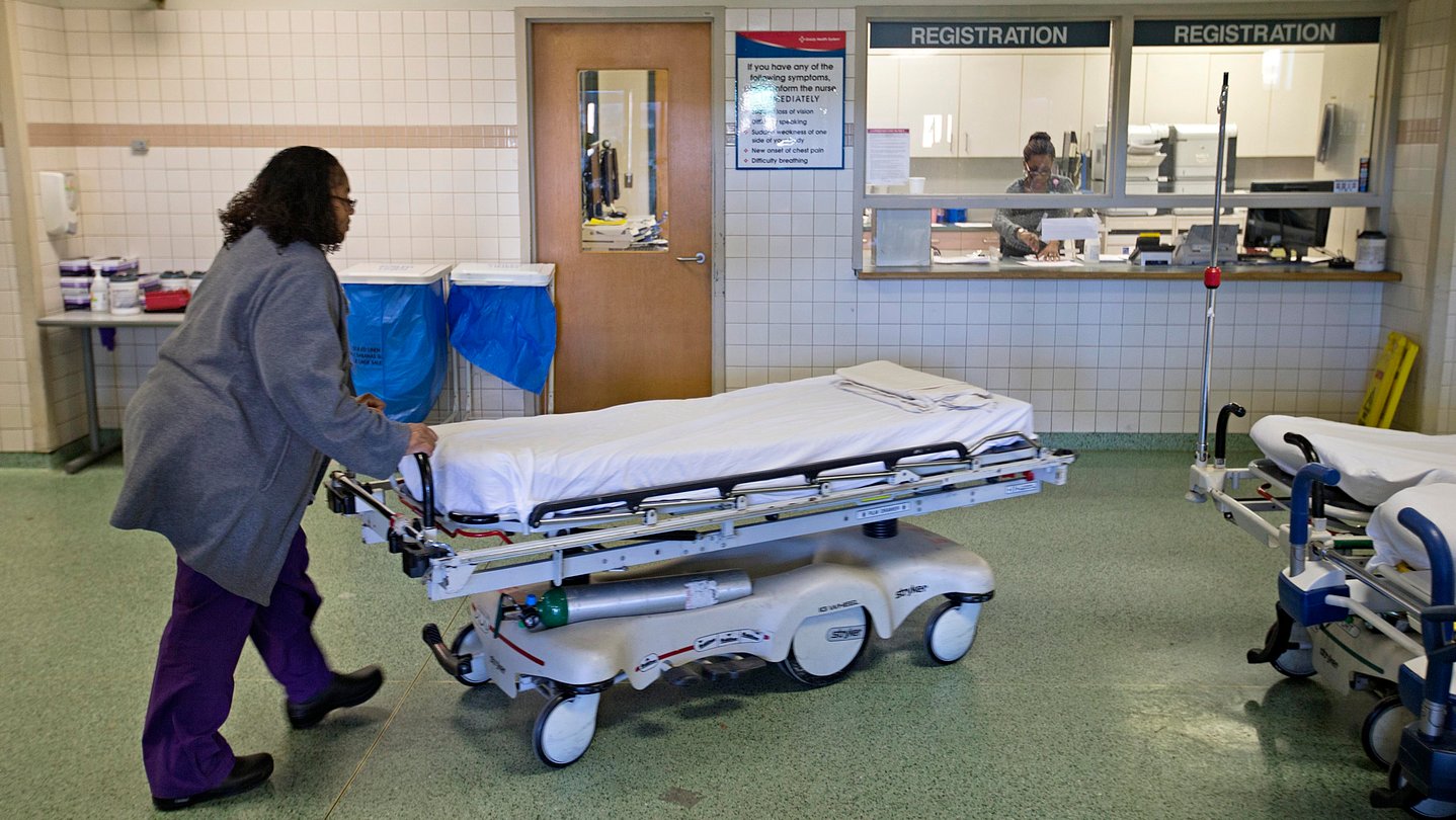 A worker wheels beds in an emergency department.