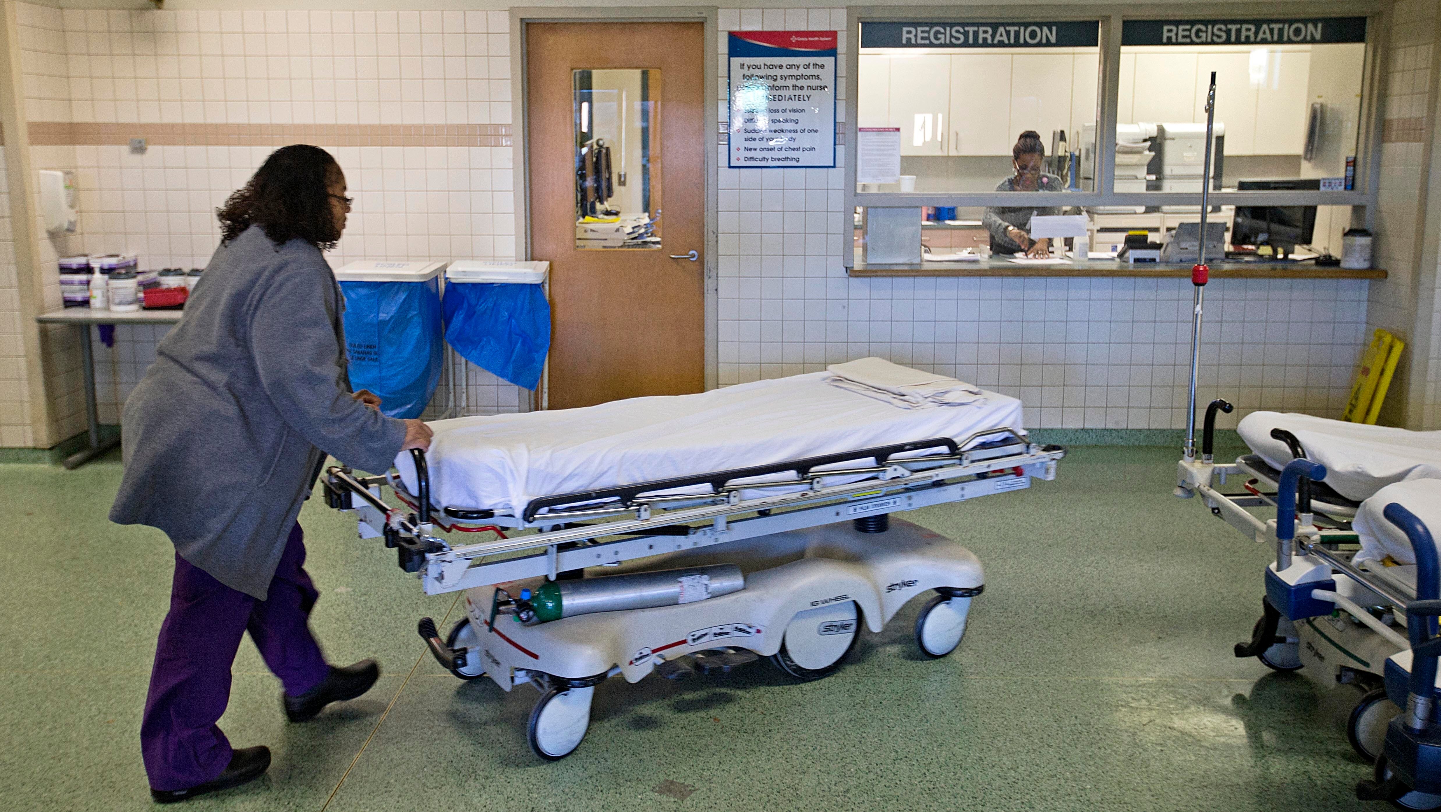 A worker wheels beds in an emergency department.