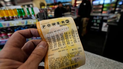 A powerball lottery ticket is held in a person's hand