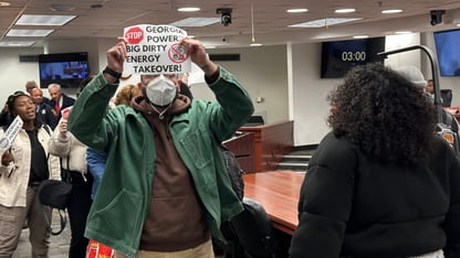A group of protesters march through a hearing room