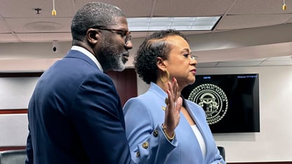 Alicia Johnson holds up a hand and puts her hand on a Bible held up by her husband