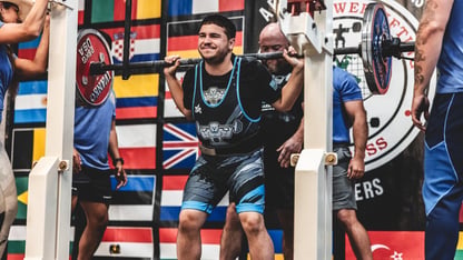 A photo of Aaron Kaminer lifting a large dumbbell weight.