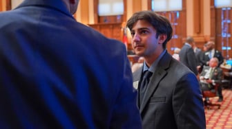Akbar Ali stands in the state House chamber, talking to another person