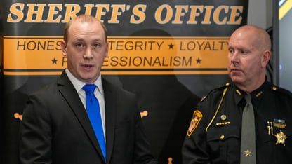 A detective and a captain stand at a news conference