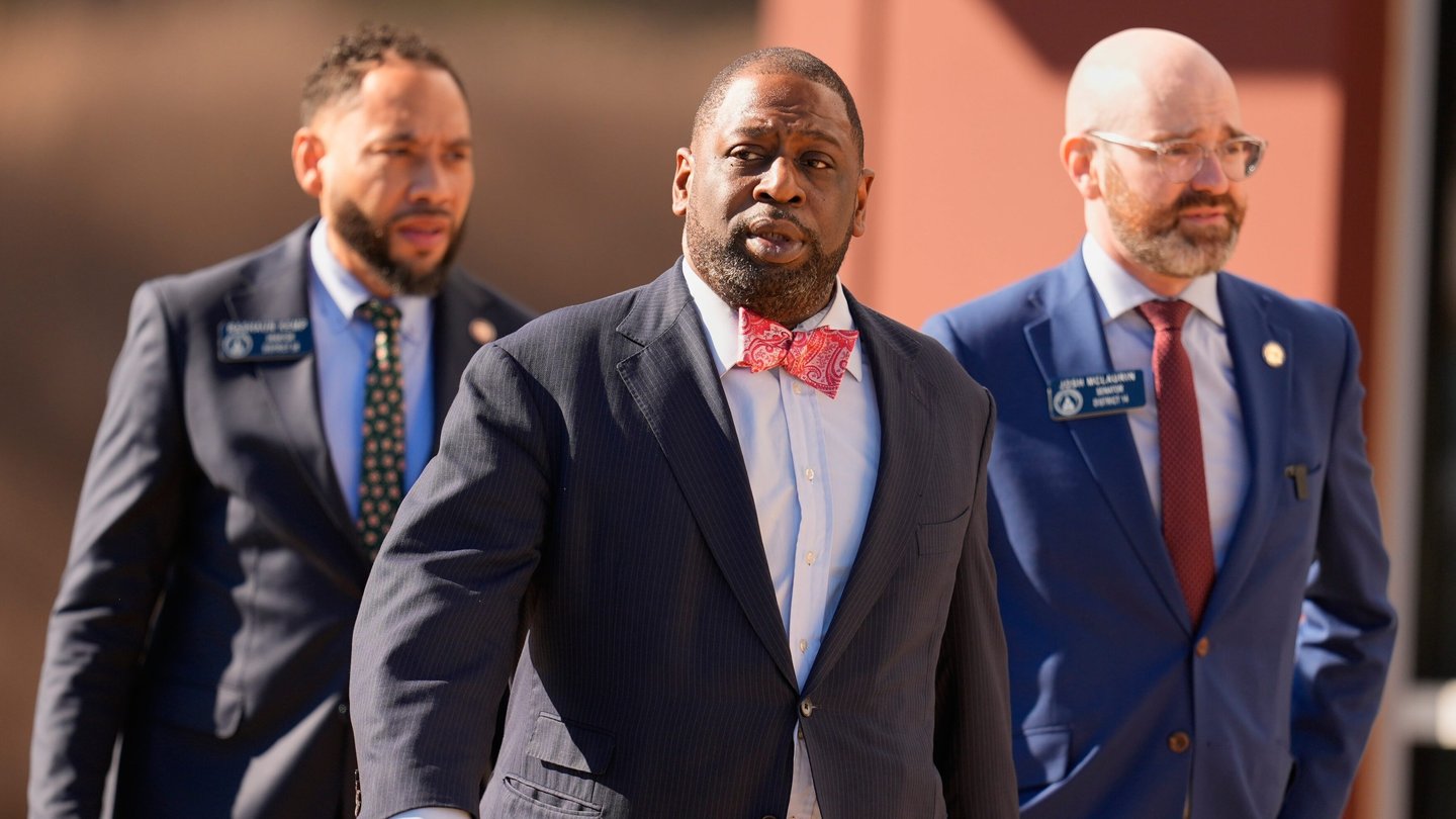 Three men in suits walk through a parking lot