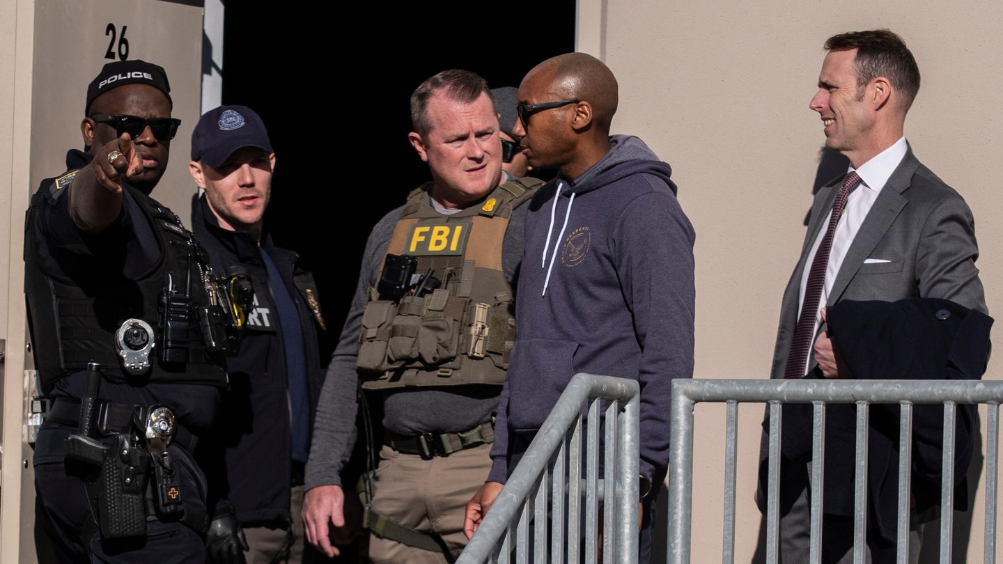 A group of law enforcement officials in uniform stand outside of a building
