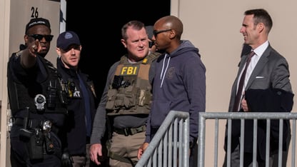 A group of law enforcement officials in uniform stand outside of a building